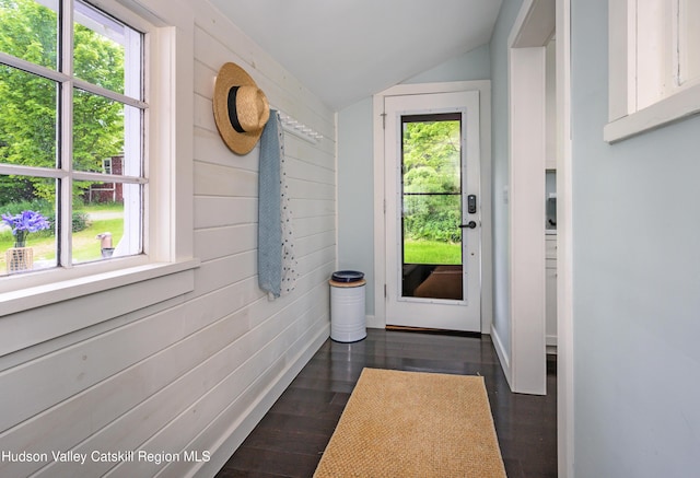 doorway to outside featuring dark hardwood / wood-style flooring, wooden walls, and lofted ceiling