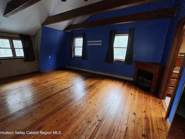 unfurnished living room featuring baseboard heating, lofted ceiling with beams, and wood-type flooring