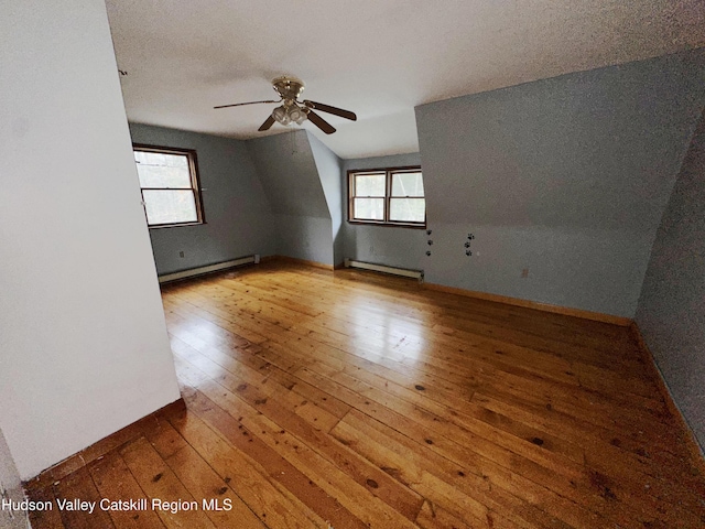 additional living space with lofted ceiling, ceiling fan, a baseboard radiator, and hardwood / wood-style floors