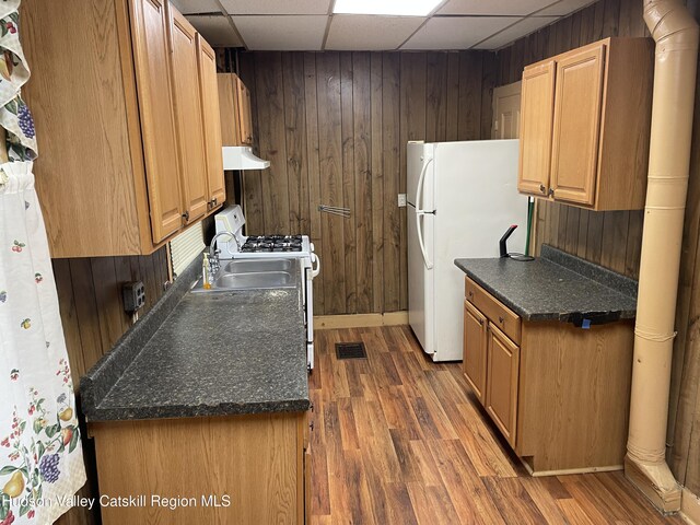 63 Gill St, Kingston, NY 12401 - kitchen featuring white appliances, under cabinet range hood, wood finished floors, a paneled ceiling, and dark countertops