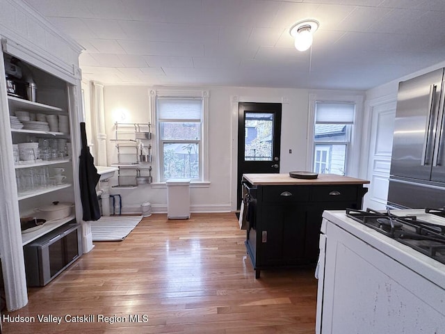 kitchen featuring white cabinets, hardwood / wood-style flooring, a kitchen island, white range with gas stovetop, and stainless steel refrigerator