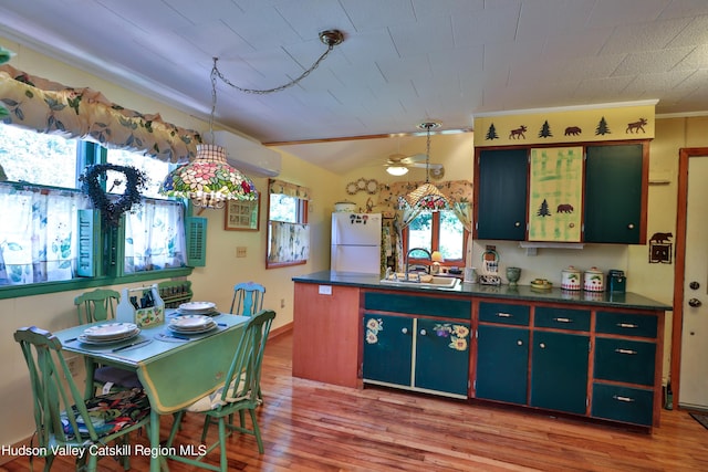 kitchen with ceiling fan, sink, white fridge, wood-type flooring, and lofted ceiling