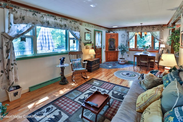 living room featuring plenty of natural light, wood-type flooring, baseboard heating, and an inviting chandelier