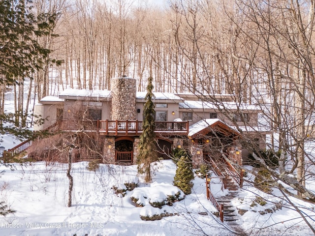 exterior space with stone siding, a chimney, and a wooden deck