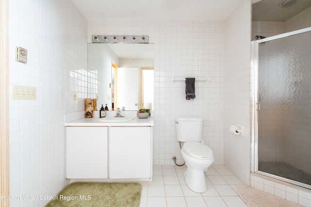 full bathroom with tile walls, toilet, vanity, a shower stall, and tile patterned floors