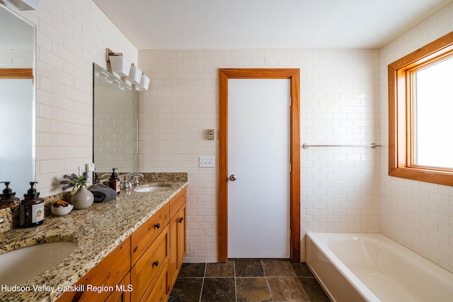 full bath with a garden tub, double vanity, a sink, and tile walls