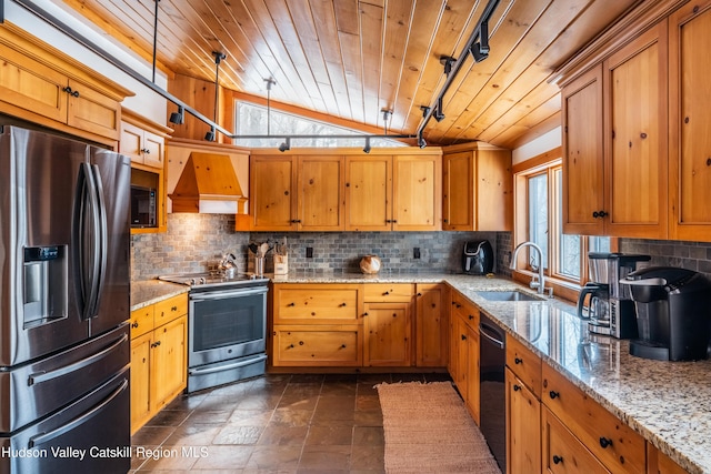 kitchen featuring light stone counters, stainless steel appliances, a sink, hanging light fixtures, and custom range hood