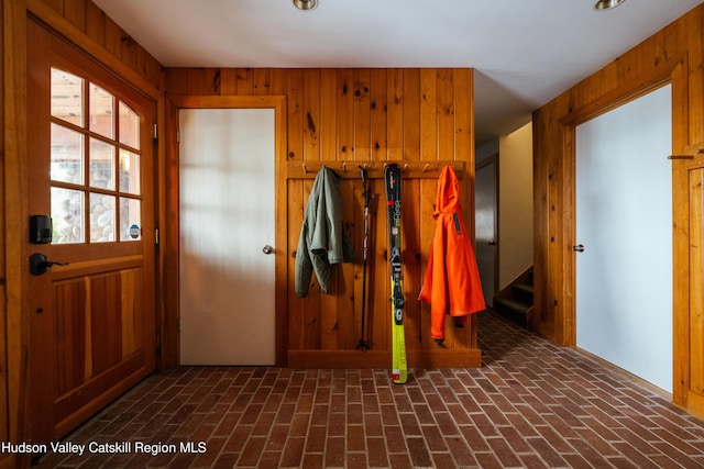 mudroom with brick floor and wood walls