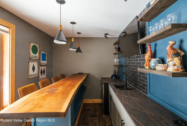 kitchen featuring a sink, baseboards, backsplash, open shelves, and dark wood finished floors