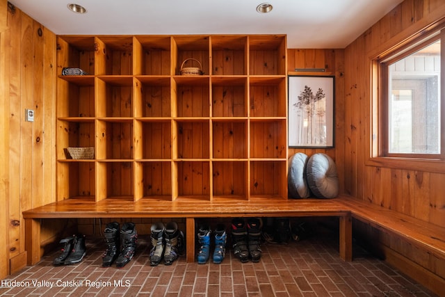 mudroom with a sauna, wood walls, and brick floor