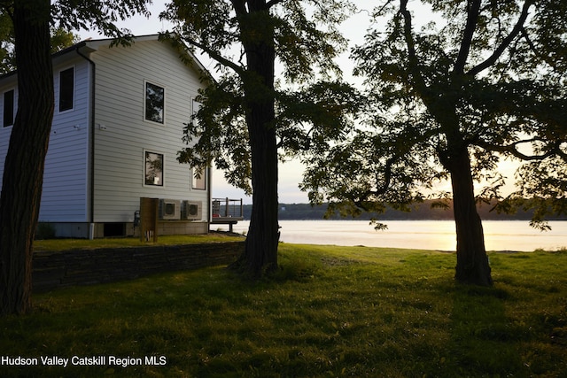 yard at dusk featuring a water view