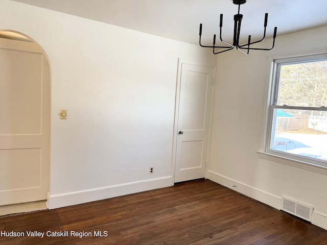 empty room featuring dark hardwood / wood-style floors and a chandelier