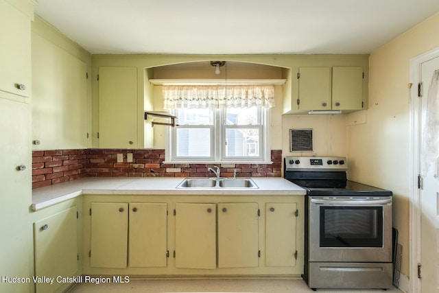 kitchen featuring sink, hanging light fixtures, stainless steel electric range oven, decorative backsplash, and cream cabinetry