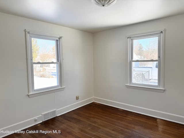 empty room featuring a healthy amount of sunlight and dark hardwood / wood-style floors