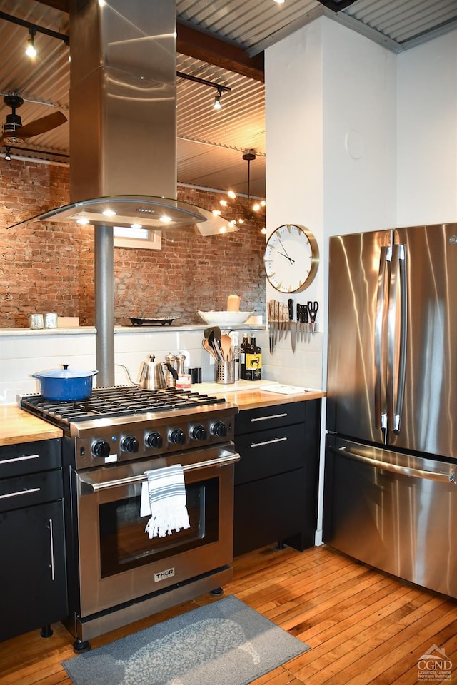 17-23 Linden St, Pittsfield, MA 01201 - kitchen featuring stainless steel appliances, brick wall, dark cabinets, island range hood, and light wood-style floors