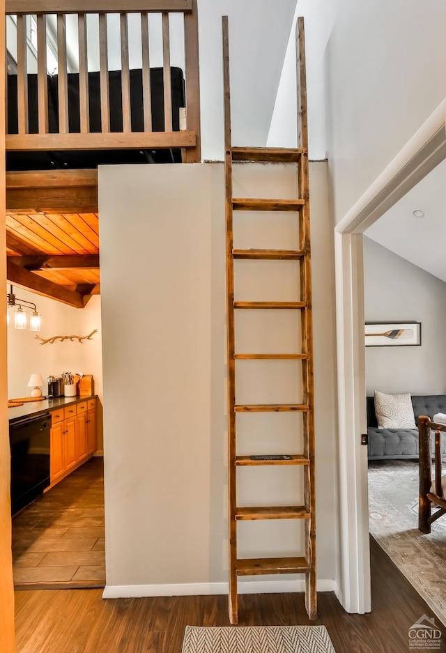 staircase featuring wood finished floors, baseboards, and vaulted ceiling