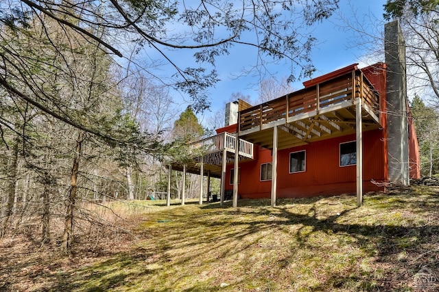 back of house with a chimney and a wooden deck