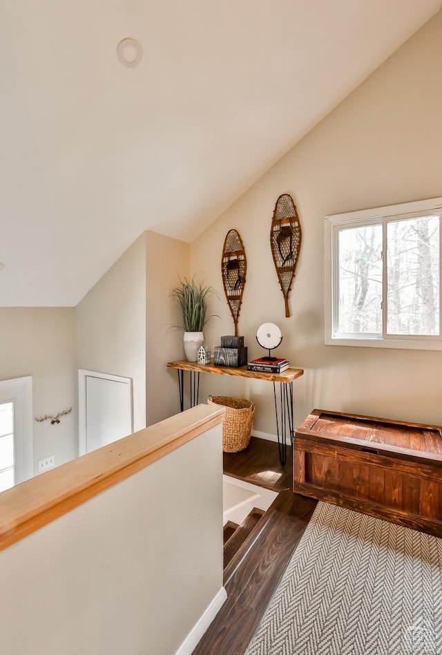 hall featuring vaulted ceiling, dark wood-type flooring, and baseboards
