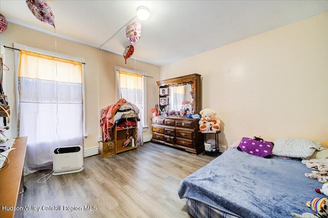 bedroom with a baseboard radiator and wood finished floors