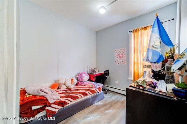 bedroom featuring a baseboard heating unit and wood finished floors