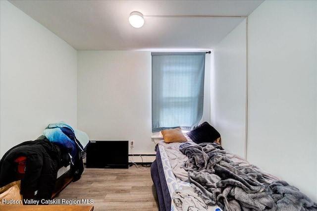 bedroom with a baseboard radiator and light wood-style flooring