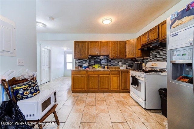 kitchen featuring white appliances, brown cabinetry, and under cabinet range hood