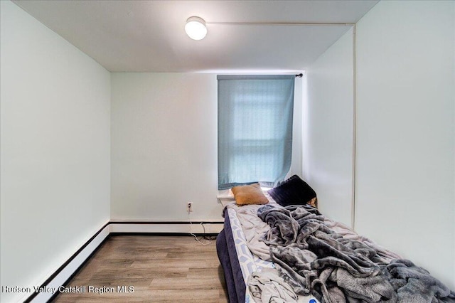 bedroom with a baseboard radiator, baseboard heating, and wood finished floors