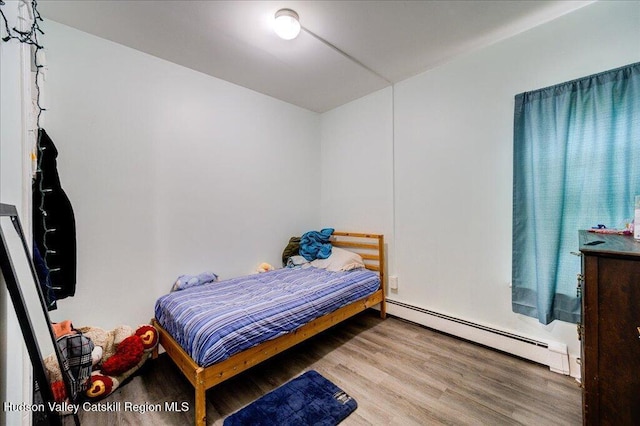 bedroom featuring baseboard heating and wood finished floors