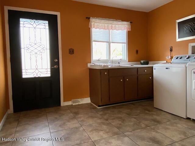 clothes washing area featuring cabinets, light tile patterned floors, washer and clothes dryer, and sink