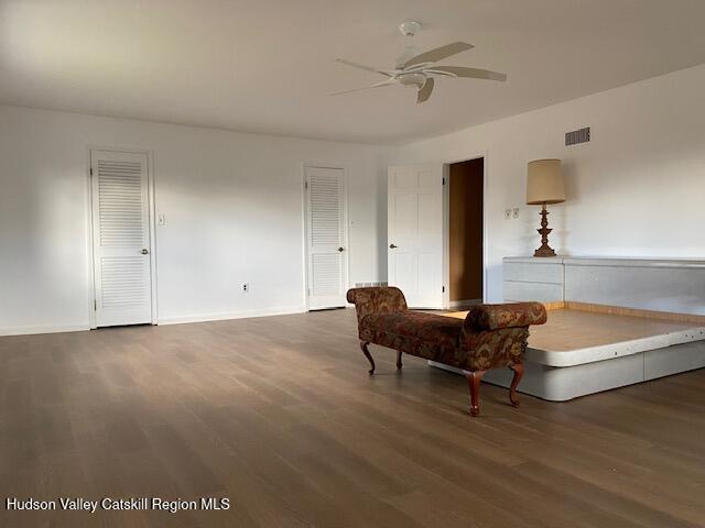 sitting room with ceiling fan and dark wood-type flooring