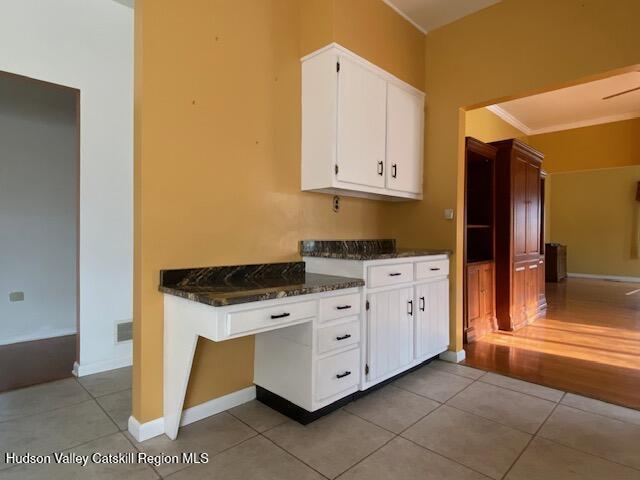 kitchen featuring dark stone counters, white cabinets, light hardwood / wood-style floors, and ornamental molding