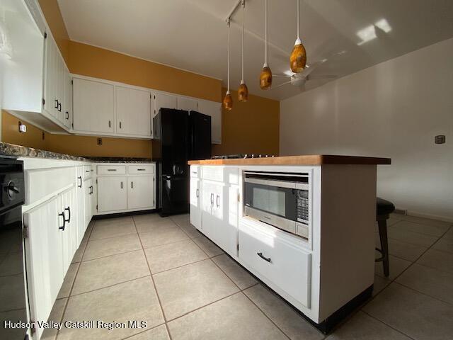 kitchen with black appliances, white cabinets, ceiling fan, decorative light fixtures, and light tile patterned flooring