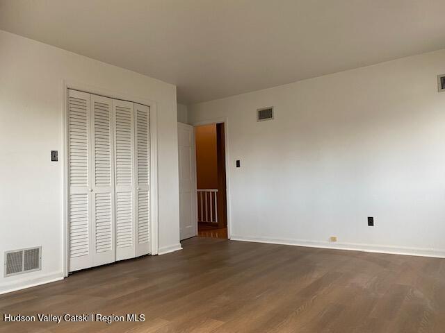 unfurnished bedroom with dark hardwood / wood-style floors and a closet