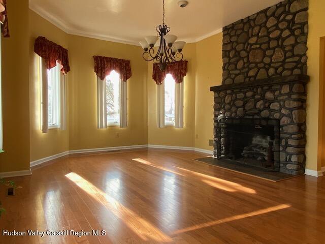 21 Lohmaier Ln, Lake Katrine, NY 12449 - unfurnished living room featuring a chandelier, wood finished floors, crown molding, and a fireplace