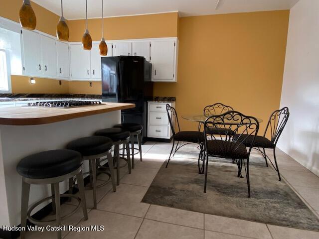 21 Lohmaier Ln, Lake Katrine, NY 12449 - kitchen with freestanding refrigerator, light tile patterned flooring, stainless steel gas stovetop, and white cabinetry