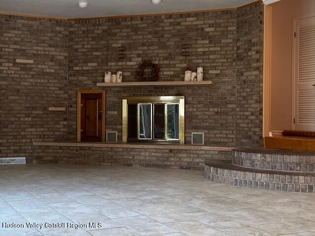 interior space with a fireplace, brick wall, and light tile patterned flooring