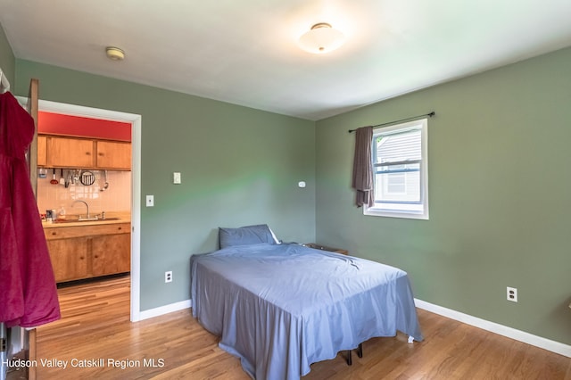 bedroom with a sink, light wood-style flooring, and baseboards