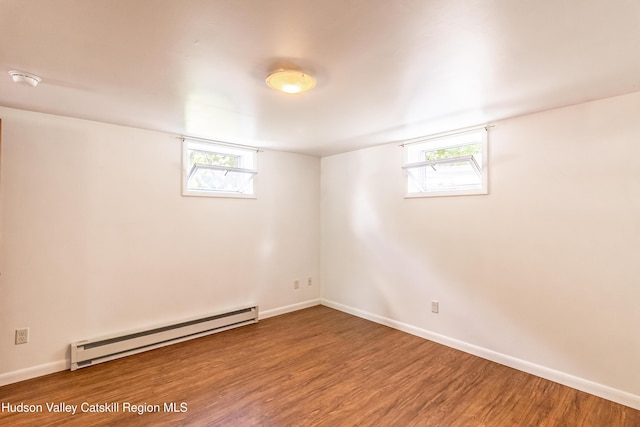 interior space featuring baseboards, plenty of natural light, a baseboard heating unit, and wood finished floors