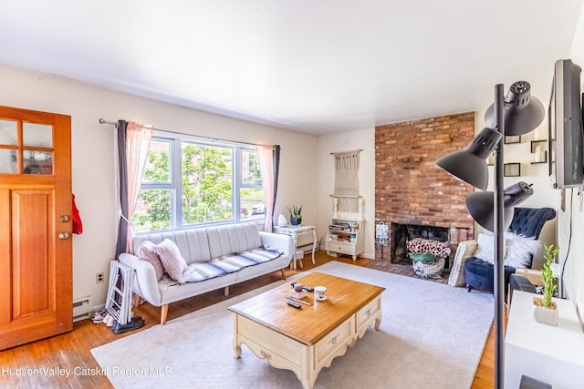 living room with a brick fireplace, light wood-style flooring, and baseboard heating