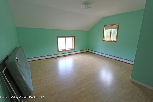 bonus room with plenty of natural light, light hardwood / wood-style floors, lofted ceiling, and a baseboard heating unit