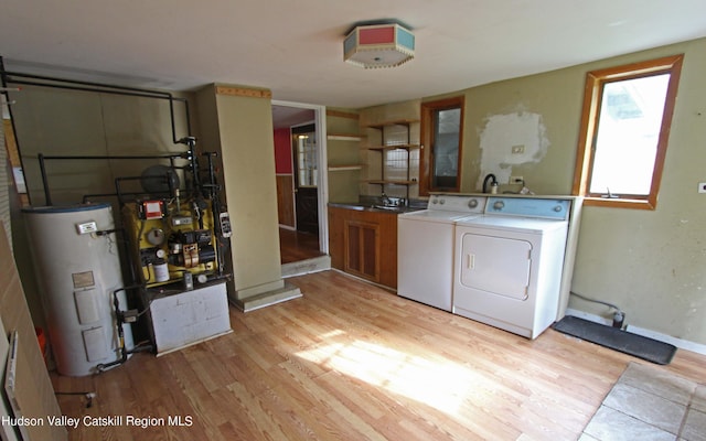 washroom featuring separate washer and dryer, water heater, cabinets, and light hardwood / wood-style floors