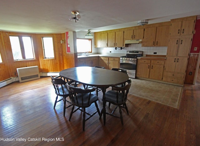 kitchen featuring gas stove, a baseboard heating unit, backsplash, wood walls, and light hardwood / wood-style floors