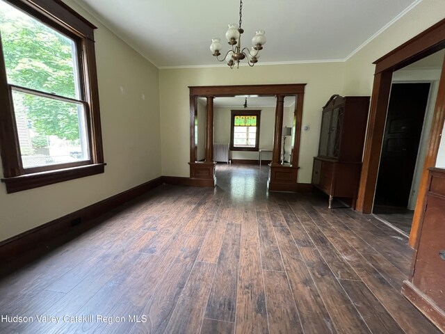 unfurnished room featuring dark wood-style flooring, baseboards, ornamental molding, a chandelier, and radiator
