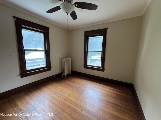 unfurnished room with baseboards, ornamental molding, hardwood / wood-style floors, radiator, and ceiling fan