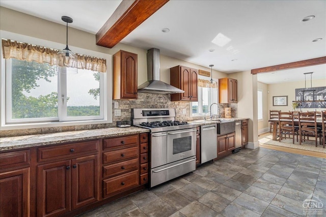  - kitchen with stainless steel appliances, wall chimney range hood, decorative backsplash, a sink, and baseboards