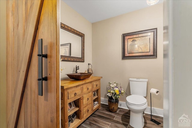  - half bath featuring toilet, wood finished floors, vanity, and baseboards