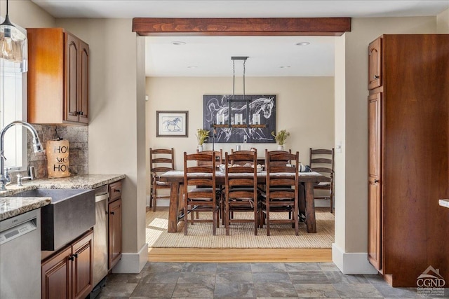  - kitchen featuring dishwasher, decorative backsplash, light stone counters, hanging light fixtures, and a sink
