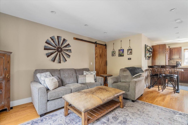  - living room featuring a barn door, light wood-type flooring, recessed lighting, and baseboards