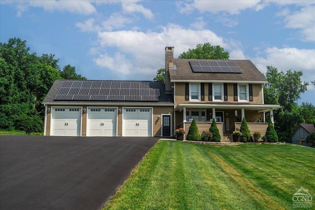  - view of front of property featuring covered porch, an attached garage, roof mounted solar panels, a front yard, and a chimney