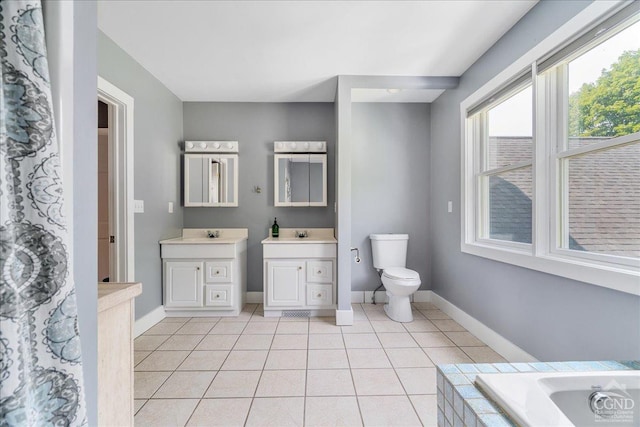  - bathroom with tile patterned flooring, toilet, baseboards, vanity, and a relaxing tiled tub